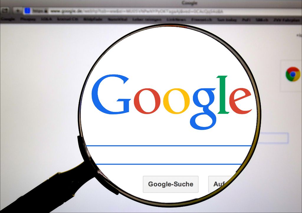 Das Google Logo und die Suchleiste unter einem Lupenglas